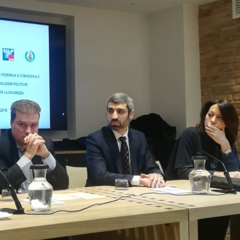 L'avvocato Davide De Matteis al tavolo dei relatori di un convegno sui maltrattamenti in famiglia a Bologna, con il logo SILP CGIL sullo schermo